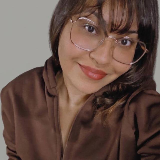 Foto da professora de inglês Jhenniffer Apolinário, sorrindo, de óculos
